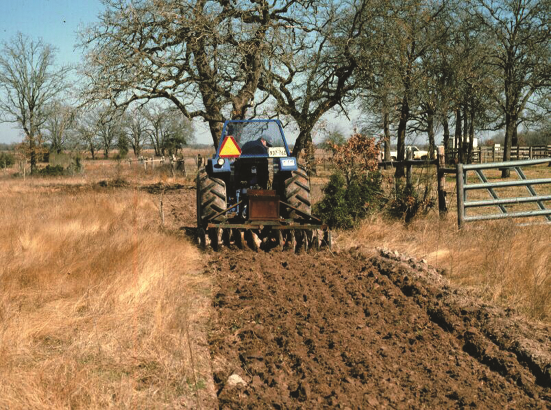 Tractor plowing a field while installing a fire break